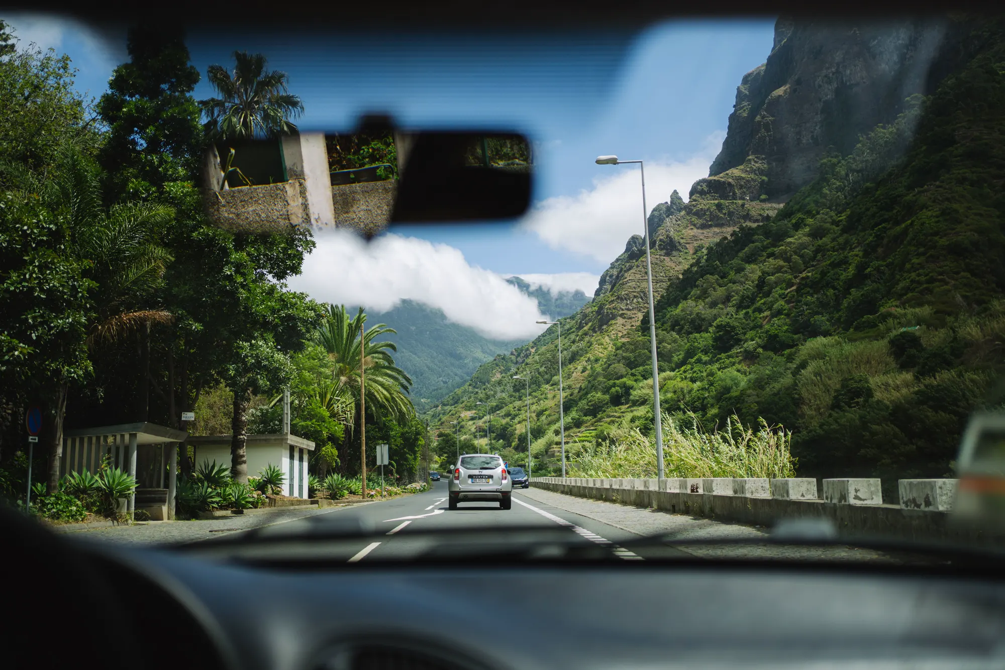 View through a car windscreen of a road through a green mountain valley on Madeira